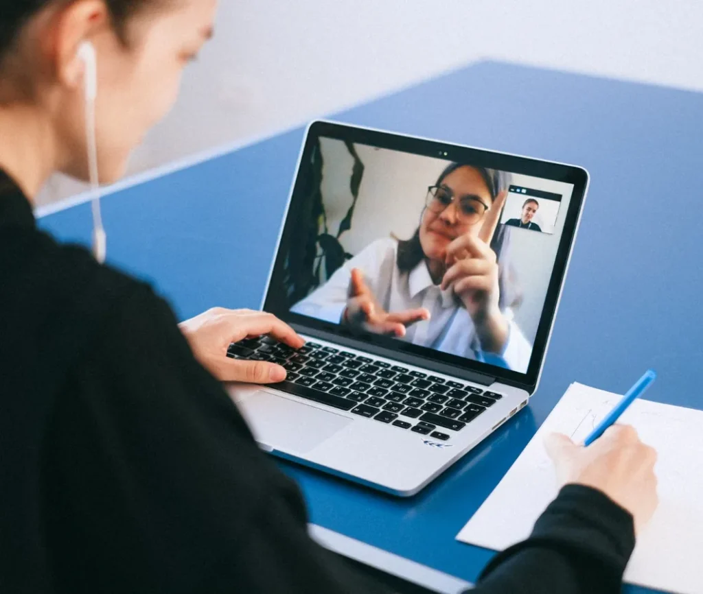 Woman taking notes during an online mediation session on her laptop