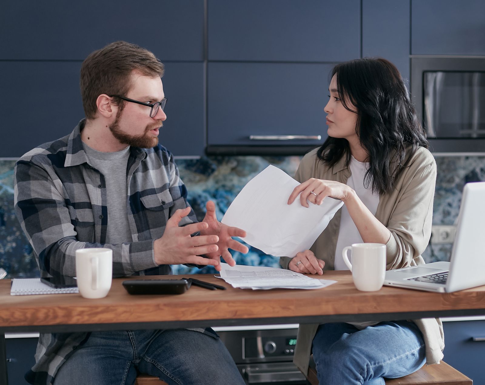 Couple in a serious discussion over paperwork at a kitchen table