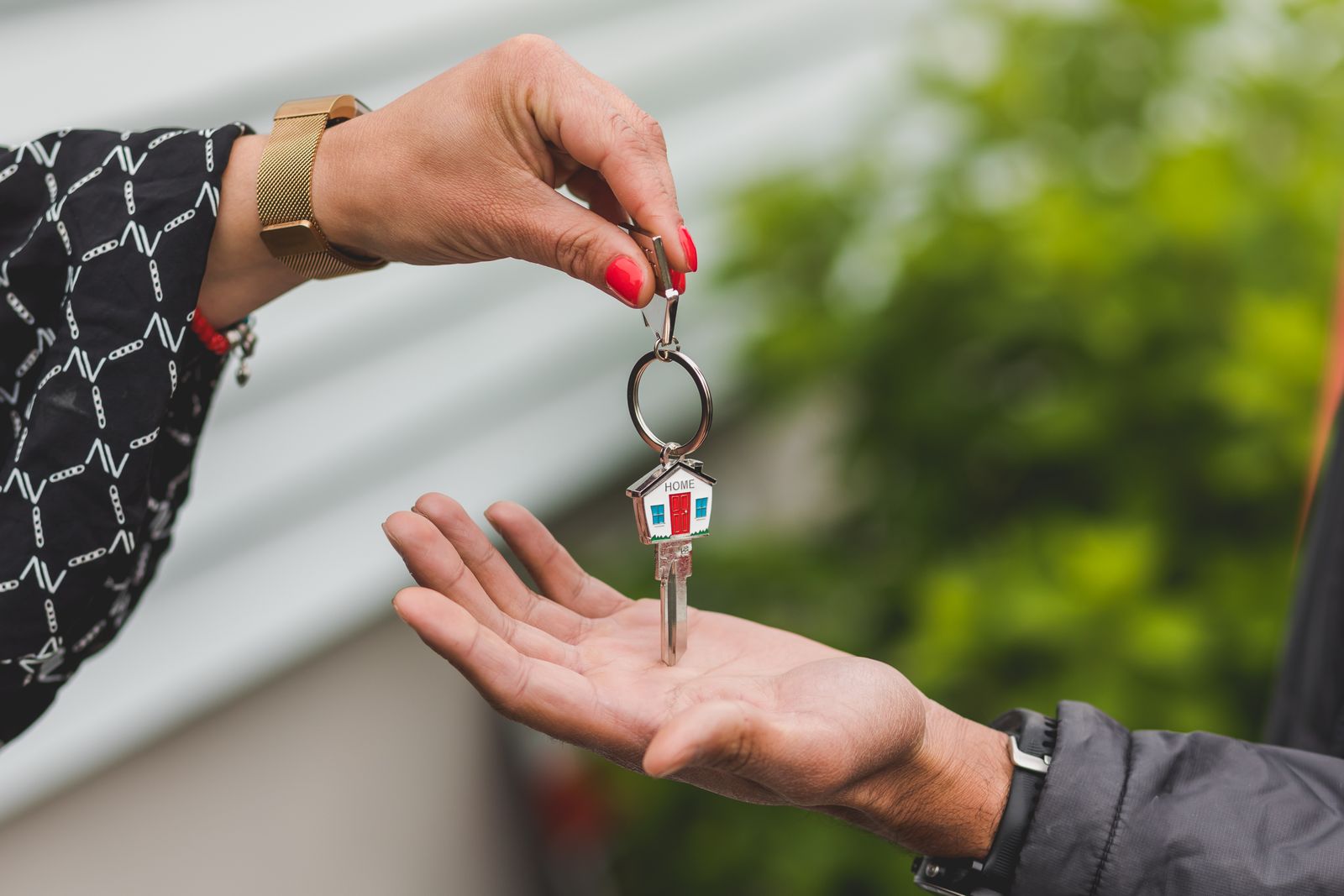 Hand passing over a house key on a house-shaped keychain